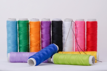 sewing needle and spooled thread on white background