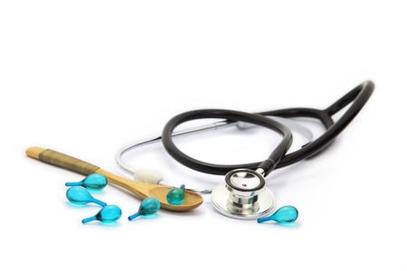 Medicine pouring from wooden spoon and stethoscope on white backgroundの写真素材