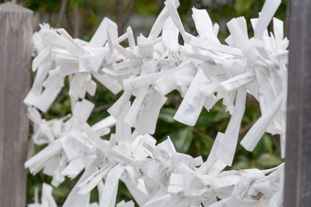 A lot of Omikuji (Japanese random fortunes written on strips of paper) are tie on string at Fushimi Inari-taisha, Kyoto Japanの写真素材