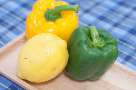 Sweet pepper and lemon on wood pan and fabric pattern backgroundの写真素材