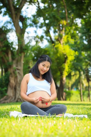 Beautiful pregnant asian woman relaxing in the parkの写真素材