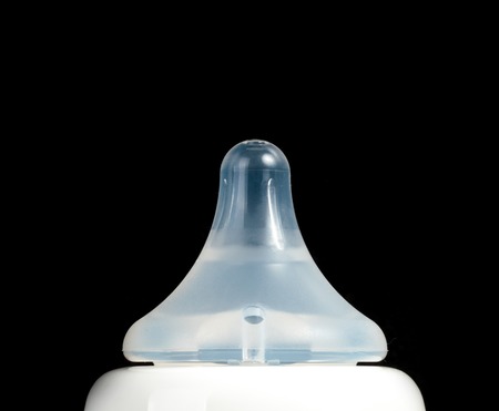 baby's feeding bottle on reflective surface on black background.の写真素材