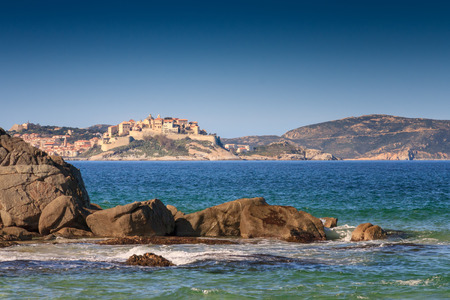 Calvi citadel taken from Plage de Petra Muna near in the Balagne region of Corsica with rocks and...