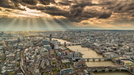 Overhead view of the skyline of London in England with the river Thames against a moody and cloudy sky with the suns rays breaking thoughのeditorial素材