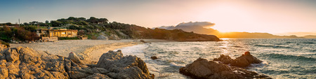 Panoramic view of Plage de Petra Muna near Calvi at sunset with rocks in the foreground, beach, mediterranean sea and Calvi in the distanceの写真素材