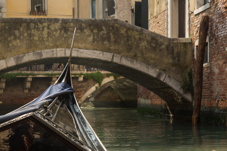 View of a bridge shot from within a gondola on a canal in Venice on a bright sunny day showing the gondola frontの写真素材