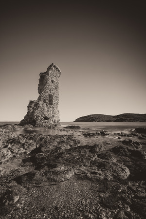 Genoese tower of Santa Maria della Chiappella at Rogliano on the east coast of Cap Corse in Corsica with rocks in the foreground on a clear blue sunny dayの写真素材