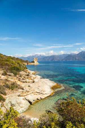 Ruins of the Genoese tower at Mortella with a turquoise mediterranean sea and rocky coastline of the Desert des Agriates near St Florent in Corsica with Cap Corse in the distanceの写真素材