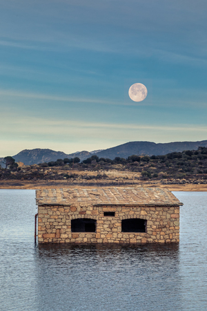 Full moon rising over partially submerged and abandoned stone building in Lac de Codole lake in the Balagne region of Corsicaの写真素材