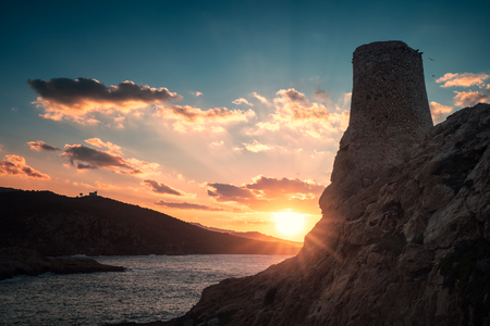 Ancient stone Genoese tower at La Pietra in Ile Rousse in the Balagne region of Corsica silhouetted by a dramatic sun setting over the Mediterranean seaの写真素材