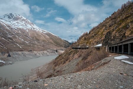Last of the winter snow on the mountains at the lake and dam on the Great St Bernard pass between...