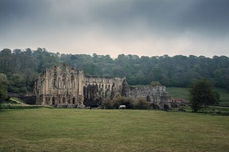 Dark clouds hang over the 11th Century ruins of Rievaulx Abbey, one of England's largest Cistercian...