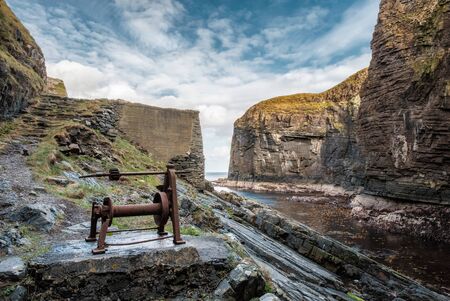 An old hand powered boat winch on the rocks at the entrance to Whaligoe Harbour near Wick in Caithness in Scotlandの写真素材