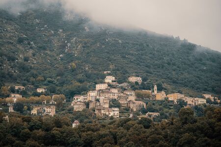 The ancient mountain village of Nessa in the Balagne region of Corsica under dark storm cloudsの写真素材