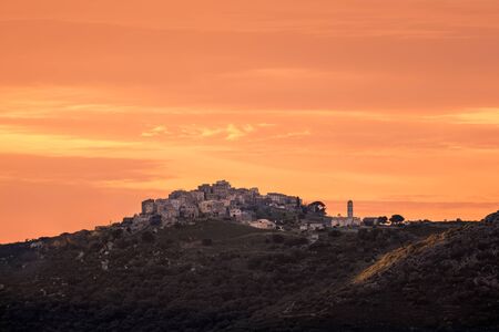 Orange sky at sunset over the ancient mountain village of Sant' Antonino in the Balagne region of Corsicaの写真素材