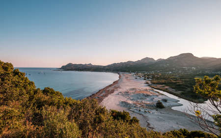 Boats moored in the bay as dawn is breaking over the beach at Ostriconi in the Balagne region of Corsica with the Desert Des Agriates in the distanceの写真素材
