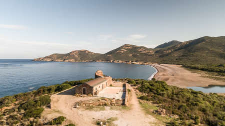 Aerial view of the 16th century Genoise tower overlooking GalÃ©ria beach and the Mediterranean sea in Corsica under a clear blue skyの写真素材