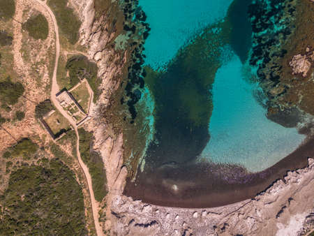 Aerial view of old stone ruin by a turquoise Mediterranean bay and PLage de L'Alga beach at La Revellata in the Balagne region of Corsicaの写真素材