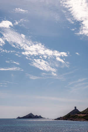 The genoese tower and lighthouse of Les Iles Sanguinaires near Ajaccio in Corsica silhouetted against a blue afternoon skyの写真素材