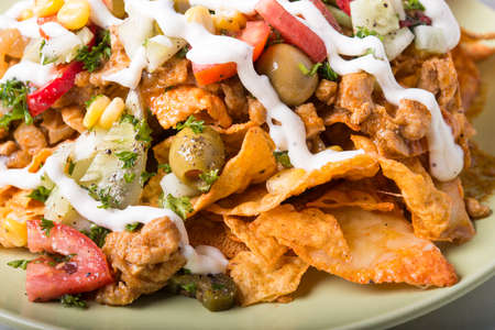 Plate of nachos with melted cheese, chicken and olivesの写真素材