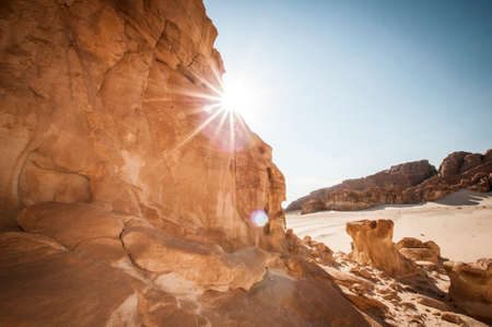 Desert landscape with blue sky and sun with sand and mountainsの写真素材