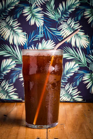 iced espreso coffee drink with tropical green leaf as backgroundの写真素材