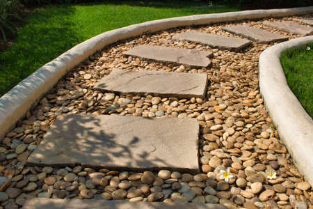 This unique photo of a beautiful curvy stone path through a meadow in a garden. the picture was taken in thailandの写真素材