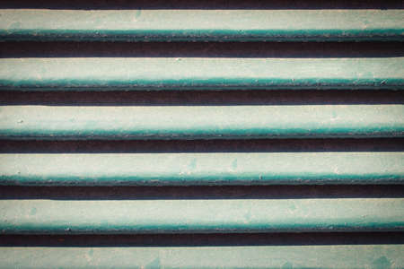 This unique photo shows a wooden shutter on a door. you can see the turquoise wooden ribs and texture very well.の写真素材