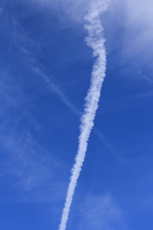 An aircraft's contrail cuts through the blue sky.の写真素材