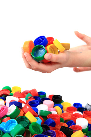 color plastic caps in human hands isolated on the white の写真素材