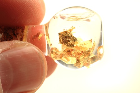 gold in glass bottle of water isolated on the white background