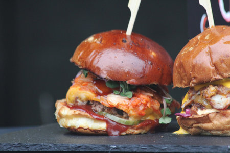 Close-up of a stacked kimchi burger, showcasing rich textures and vibrant colors on a dark slate