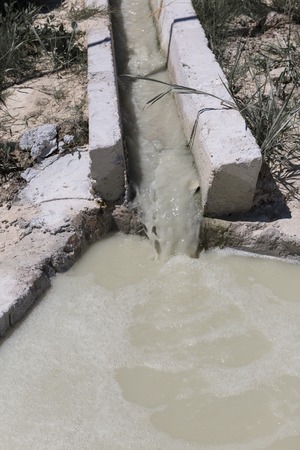 Dirty brown water flowing down the gutter in cleaning the pool. Vertical photo.の写真素材