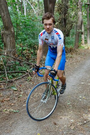 Chisinau, Republic of Moldova - July 16, 2017: cyclist at team Katusha rides a bicycle along a forest road. Looking at the camera. Vertically framed shot.のeditorial素材