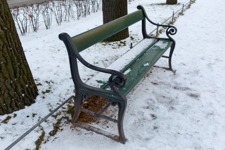 Green bench in winter. Horizontally framed shot.