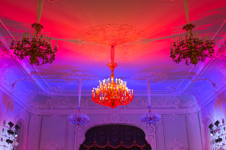 Stylish antique chandelier lit in pink and blue light. Horizontally framed shot.の写真素材