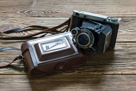 Chisinau, Republic of Moldova - March 14, 2018: The old Soviet medium format rangefinder camera Moskwa-5 and leather case. Wooden background. Horizontally framed shot.のeditorial素材