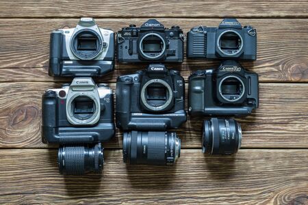 Chisinau, Republic of Moldova - March 14, 2018: different models of Canon cameras and lenses. Wooden background. Horizontally framed shot.のeditorial素材