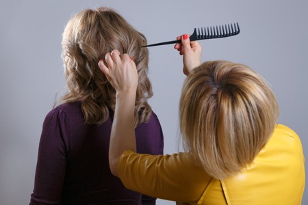 Hair salon. Woman hairstyle. Hairdresser combing hair of client. Rear view. Horizontally framed shot.の写真素材