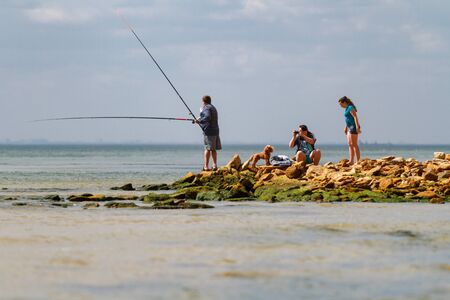 Odessa, Ukraine - August 31, 2013: Family life on the wild beach. Father is engaged in fishing. Horizontally framed shot.のeditorial素材