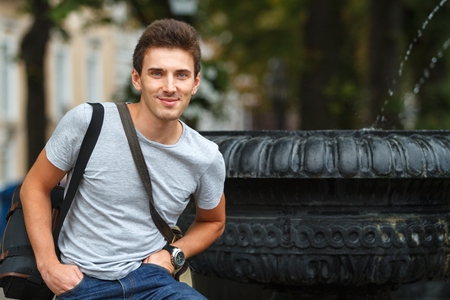 Portrait of a young man on background of fountain. Horizontally framed shot.の写真素材