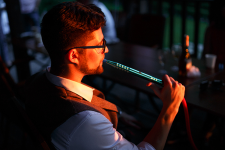 Man with glasses. He smokes hookah. Horizontally framed shot.の写真素材