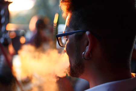 Man with glasses. He smokes hookah. Rear view. Horizontally framed shot.の写真素材