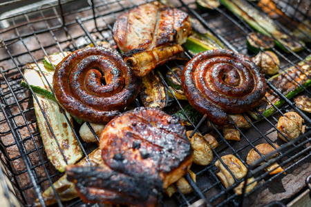 Twisted sausages, pork steak, mushrooms and zucchini cooked on grill. Horizontally framed shot.の写真素材