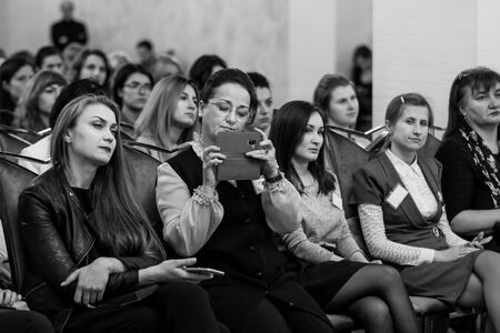 Chisinau, Republic of Moldova - March 29, 2018: audience in hall at a business conference. The participant records what is happening on the smartphone. Horizontally framed shot.のeditorial素材