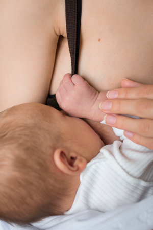 Mother breast feeding and hugging her baby. Happy family life. Man was born. Vertically framed shot.の写真素材