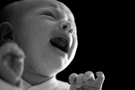 Portrait of a newborn boy. Screaming and crying. Man was born. Family life. On black background....