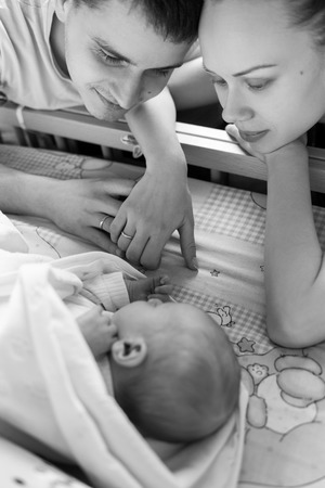 Woman and man look at newborn. Boy sleeps in his crib.の写真素材