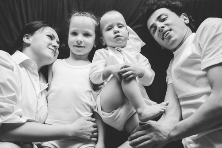 Parents and their children lie on a black sheet. Black and white photo.の写真素材