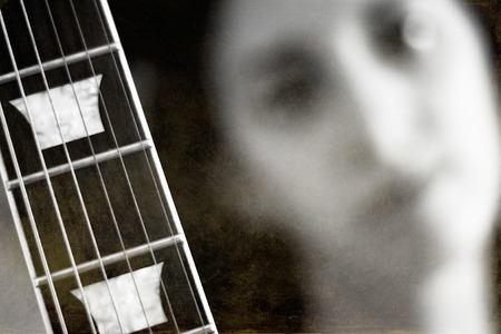 In foreground neck of guitar. In background face of a sad women. Black and white photo.の写真素材
